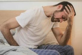 young man in sleepwear suffering from headache in morning